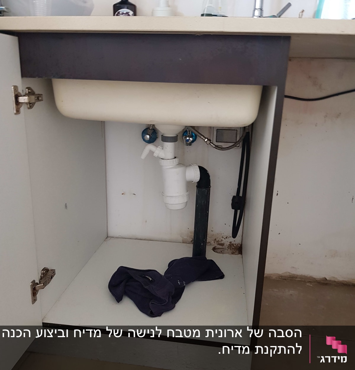 כיור מטבח עם צנרת פתוחה וארון תחתון
